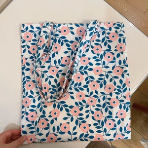Detail of floral canvas tote bag featuring pink blossom patterns and blue leaves