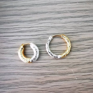 Macro detail of mixed metal hoops featuring a hammered texture and two-tone finish