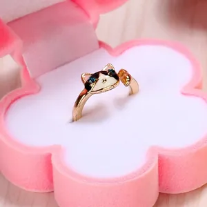 Macro shot of gold cat ring with enamel details inside a pink flower flocking jewelry box