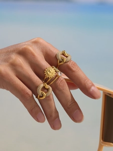 Detailed view of gold sun relief ring and chain zircon band on hand at beach