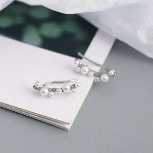 Close-up of elegant silver branch earrings with white pearls and sparkling rhinestones