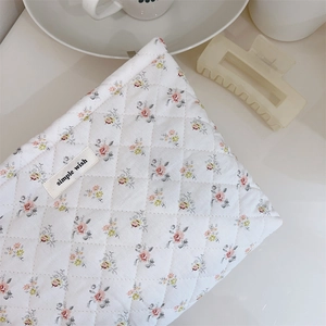 Detail view of floral quilted cotton makeup bag with simple wish brand woven label