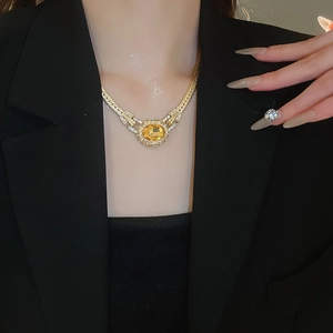 Detail of vintage gold oval pendant necklace with amber gemstone and crystals on model