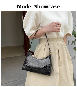 Detail of black crocodile texture baguette bag with golden hardware on a model