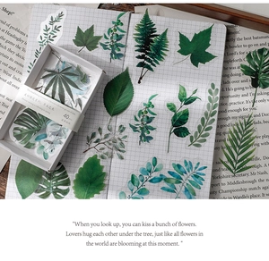 Detailed flat lay of 40 botanical stickers with green leaves on a grid journal paper