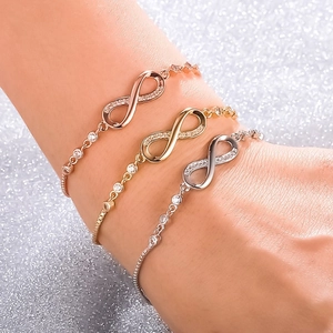 Three-color infinity bracelets in gold, rose gold and silver with zircon on glitter background