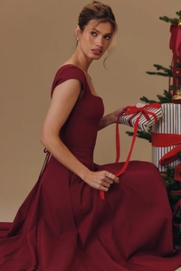Détail d'une robe rouge à col carré avec une boîte cadeau à ruban dans un décor festif