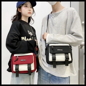 Close-up of canvas crossbody bag featuring contrast stitching and plastic buckle closure