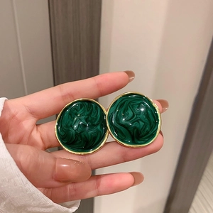 Macro shot of retro dark green marble texture round stud earrings with gold trim