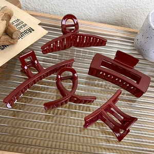 Set of five festive burgundy hair claws in various styles on a textured backdrop