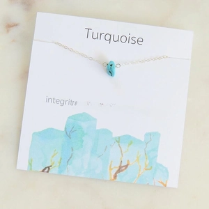 Detailed macro view of a turquoise pendant necklace on a symbolic message card