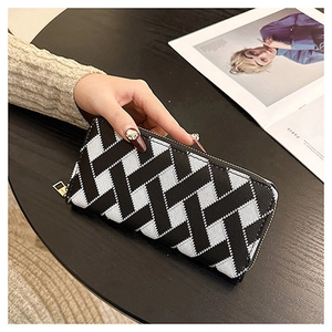 Detail of a woven long wallet with black and white cross pattern and metal zipper closure