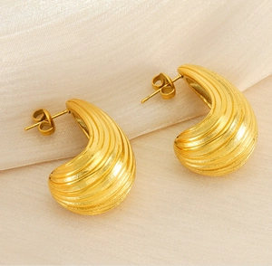 Detailed macro view of gold-plated teardrop earrings with textured horizontal stripes
