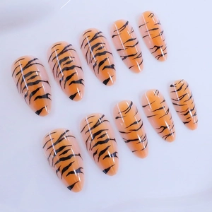Tiger print almond press-on nails in glossy orange and black animal pattern design