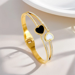 Detail of 18K gold-plated bangle featuring black and white heart charms and pavé diamonds