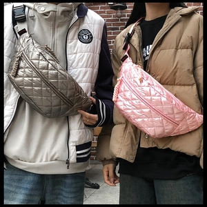 Close-up of quilted waist bags in silver and pink colors worn by models in city street
