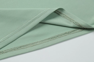 Macro view of mint green knit fabric showing detailed hem stitching and fine texture