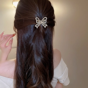 Detail of elegant hollow butterfly hair claw clip with pearls on a model back hair