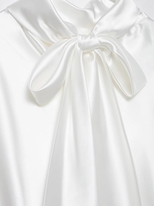 Vista dettagliata dell'elegante scollatura in raso bianco con un design a fiocco alla moda