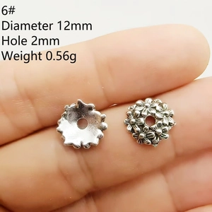 Detail of 12mm silver flower bead cap showing 2mm hole size and embossed metal texture