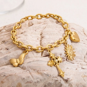 Detail of 18K gold plated bracelet with butterfly, heart, sun, and cross charms on stone