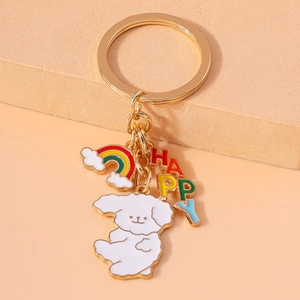 Close-up of golden keychain with white dog charm, rainbow cloud, and colorful HAPPY letters