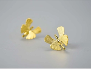 Macro shot of golden butterfly earrings with textured brushed metal finish and 3D design
