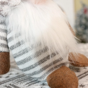 Macro shot of fluffy white plush beard and grey striped knit sweater on gnome doll