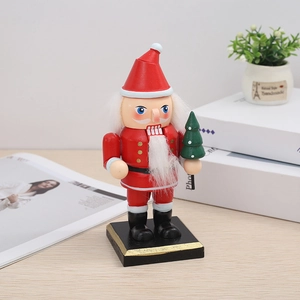 Detail of wooden Nutcracker figurine in Santa outfit holding a small Christmas tree