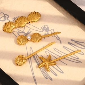 Detail of 4-piece gold starfish and shell hair clips set with pearls on white backdrop