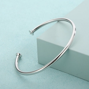 Minimalist silver stainless steel open bangle displayed on a geometric cube stand