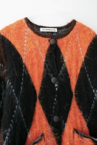 Détail du cardigan en tricot à losanges orange et noir avec boutons marron foncé