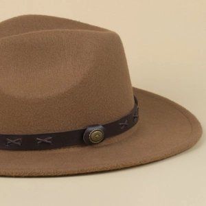 Detail of a brown fedora hat featuring a vintage leather band with metal rivets