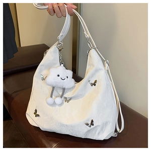 Detail of white textured shoulder bag featuring silver butterfly and cloud charm