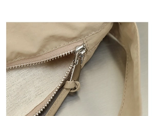 Dettaglio del tessuto in nylon e della cerniera in metallo argentato della borsa beige
