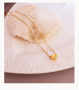 Detailed view of a golden heart pendant necklace on a decorative white ceramic plate