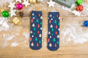 Close-up of navy knit Christmas socks with tufted tree patterns on a festive wooden surface