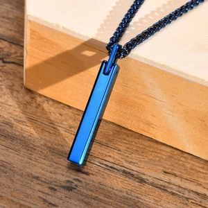 Detail of blue rectangular tungsten pendant with black woven wax rope on a wooden desk