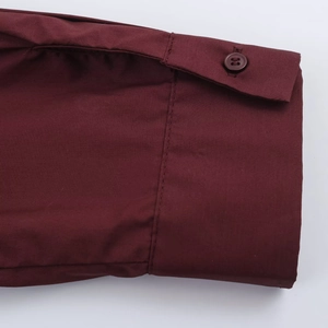 Macro detail of wine red poplin shirt cuff featuring a matching four-hole button