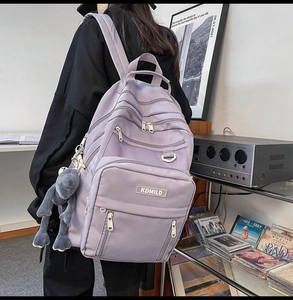 Vista posteriore di uno zaino scolastico viola ad alta capacità con logo e peluche