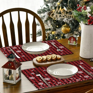 Red and black plaid Christmas placemats with snowflake patterns on a wooden dining table