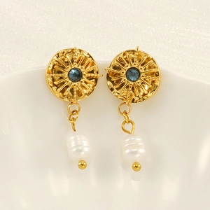 Detail of bohemian gold starburst earrings with blue crystal and white pearl charms
