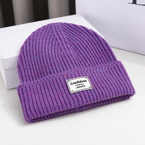 Detailed close-up of purple knit beanie with vertical texture and stylish label