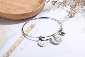 Detail of silver heart charm bracelet with Love mi mama engraving on wooden tray
