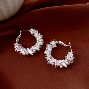 Détail de boucles d'oreilles créoles argentées géométriques avec diamants rectangulaires