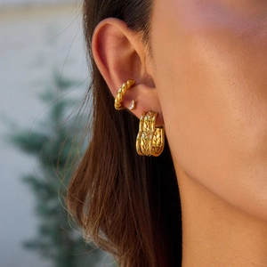 Detail of 18K gold stainless steel triple-layer hoop earrings on a model's ear