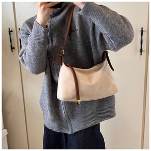 Detail of beige suede shoulder bag featuring dark brown leather strap and side tie knots