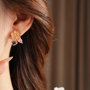Detail of flower stud earring with pink resin petals and dangling colorful zircons