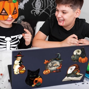 Close-up of Halloween gnome and pumpkin magnetic stickers on a laptop surface