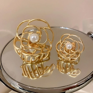 Detail of gold hollow flower hair claw clips with white pearls on a mirror surface